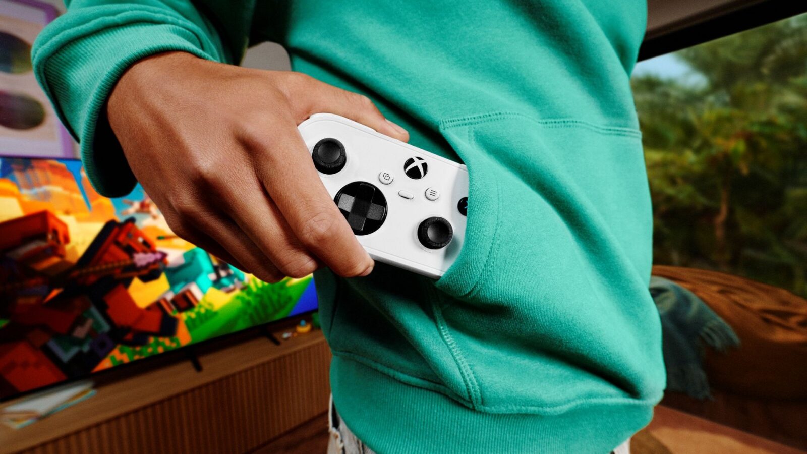 Official Xbox Wire hero image of the Xbox Nano Controller, a hand pulling the small white gamepad out of a hoodie pocket